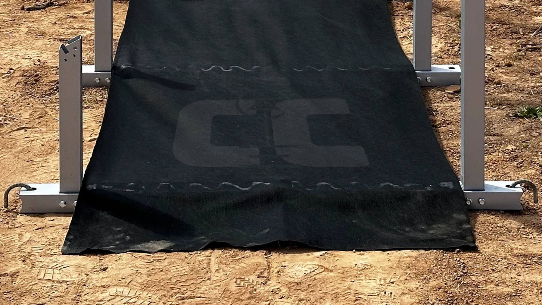IntegraRack EarthBallast geotextile draped over a BallastRack frame on bare dirt