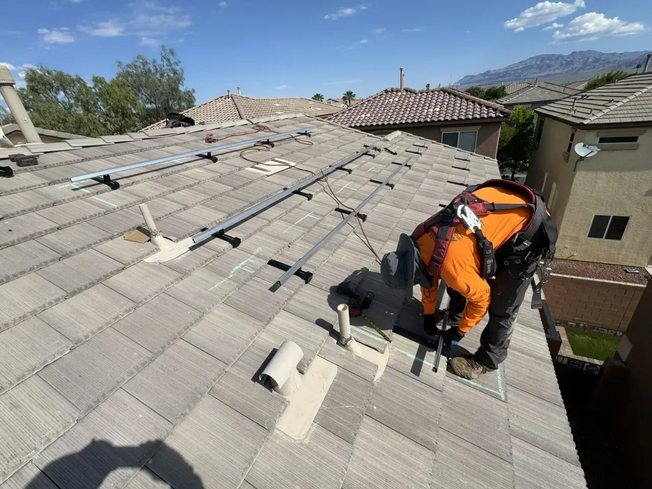 Rooftop installation of IntegraRack IR-T1 mounting brackets with the rails attached and installer bent over finishing the last mount