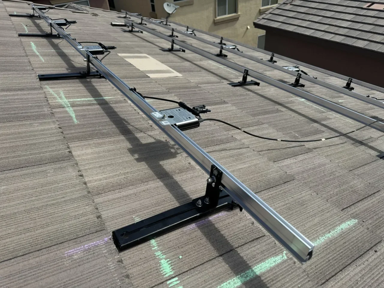 Close up view of the attachment of the IR-T1 mounting bracket holding the racking rail with microinverter attached, with solar panel removed