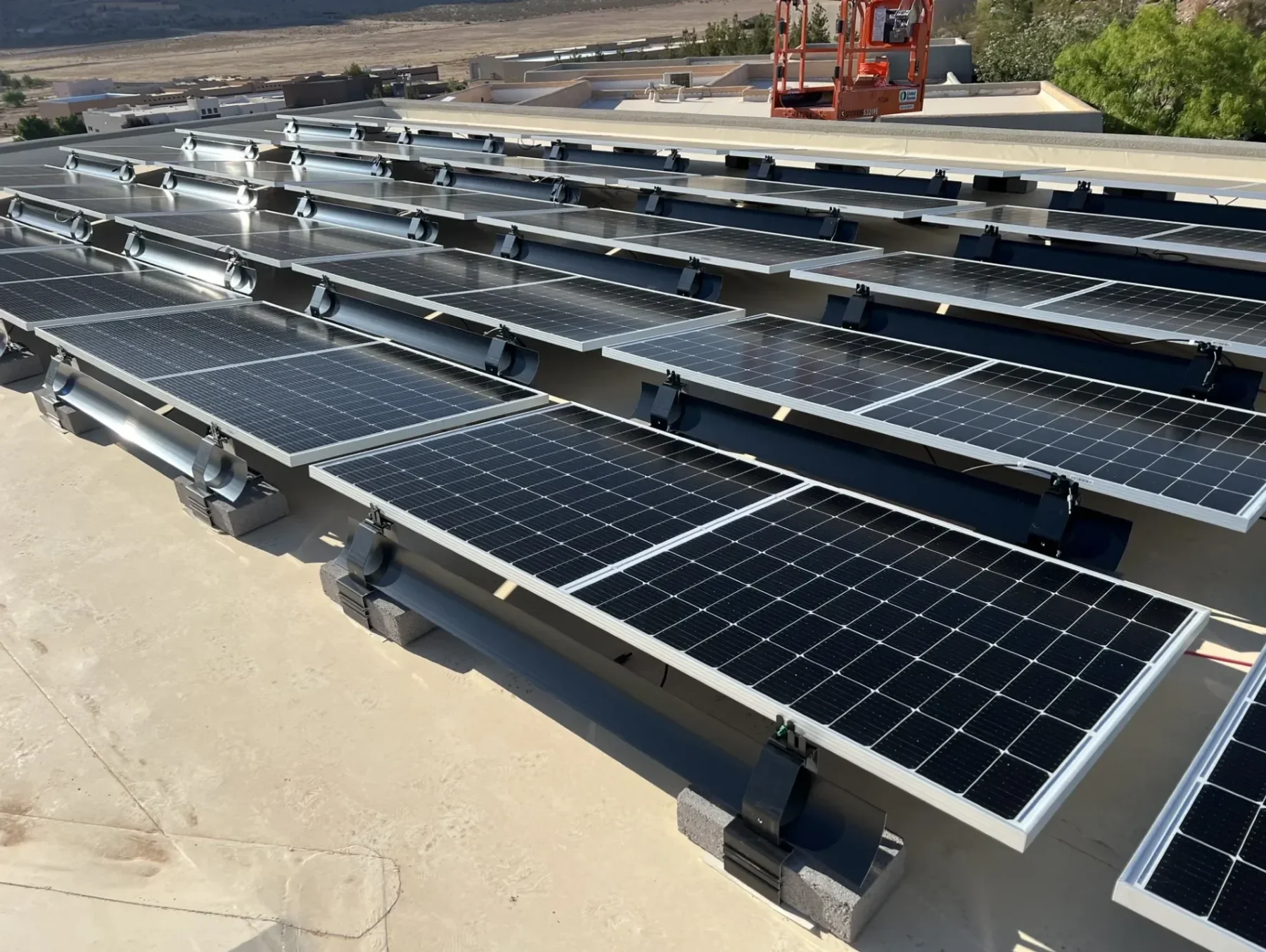 Multiple arrays of solar panels are set up on a flat surface using the IR-08MBCB ballast mount, using cinder blocks as the ballast method. Tilted rear view.
