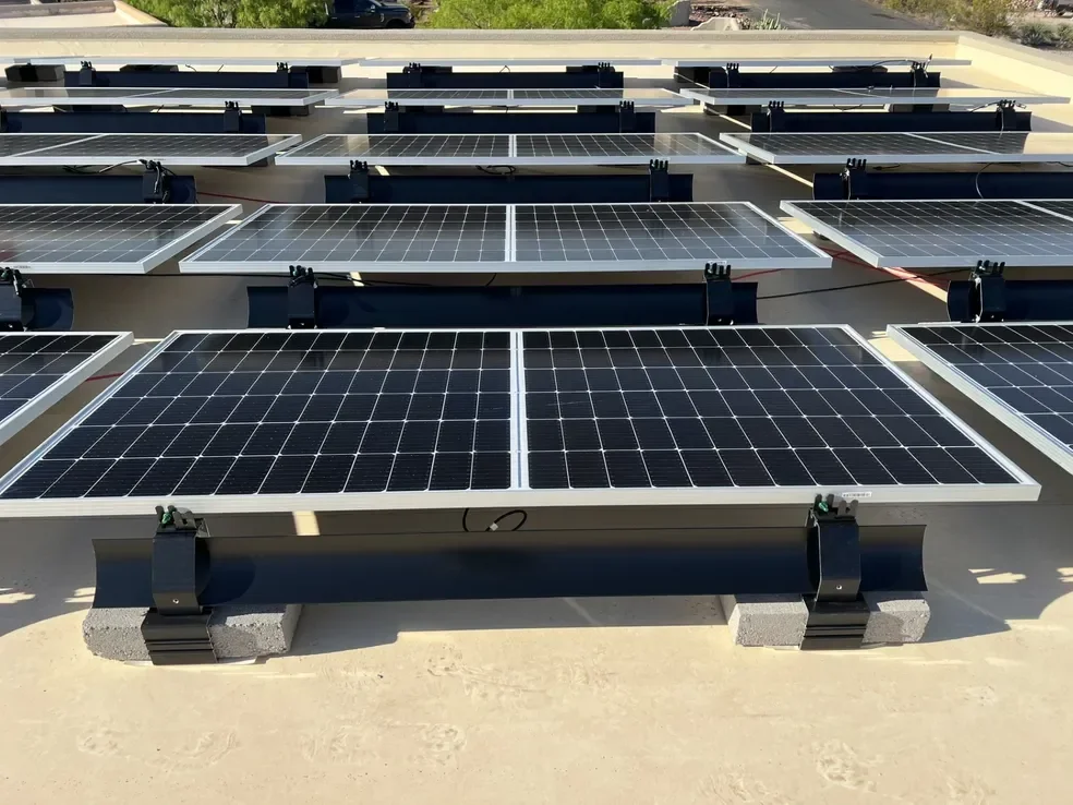 Multiple arrays of solar panels are set up on a flat surface using the IR-08MBCB ballast mount, using cinder blocks as the ballast method. Rear view.
